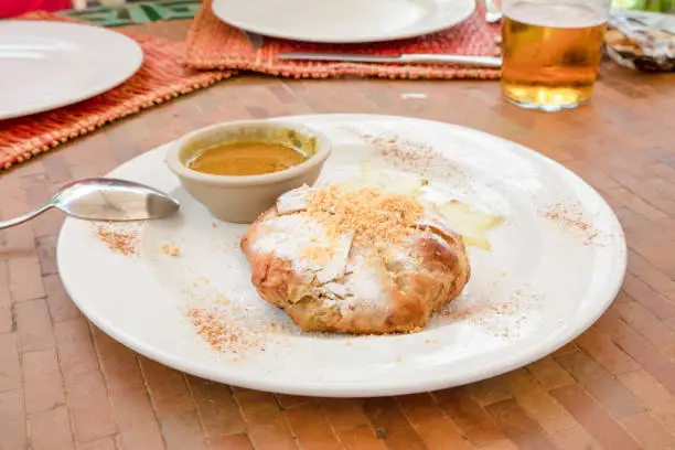 Moroccan chicken bisteeya, traditional Berber meat pie with almond, cinnamon and sugar, also known as bastilla and bsteeya, in a white dish with spoon