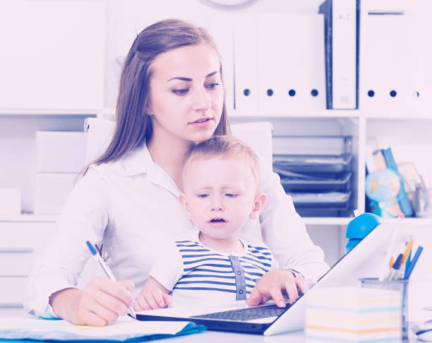 istock Mom with kid is working behind laptop 1072518490