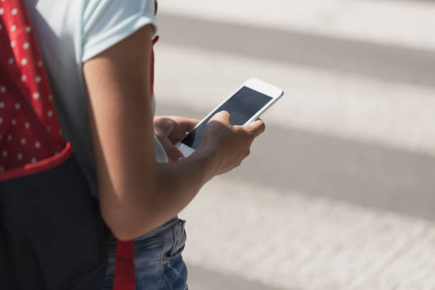 istock Close-up on a kid with a smartphone while walking through pedestrian crossing 1072518898