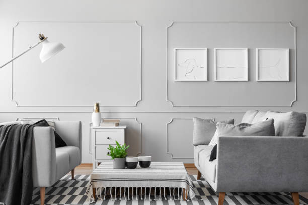 istock Posters on the empty grey wall of simple living room with two sofas, coffee table and white lamp, real photo 1072525172