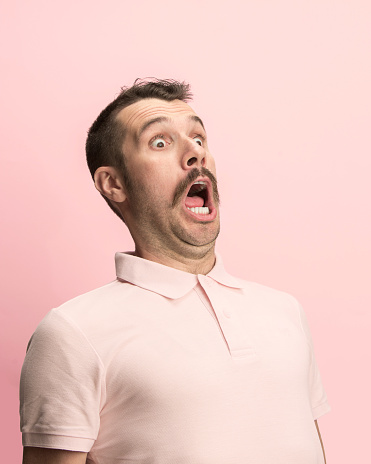 El hombre gritando con la boca abierta aislada sobre fondo rosa, emoción de cara concepto photo