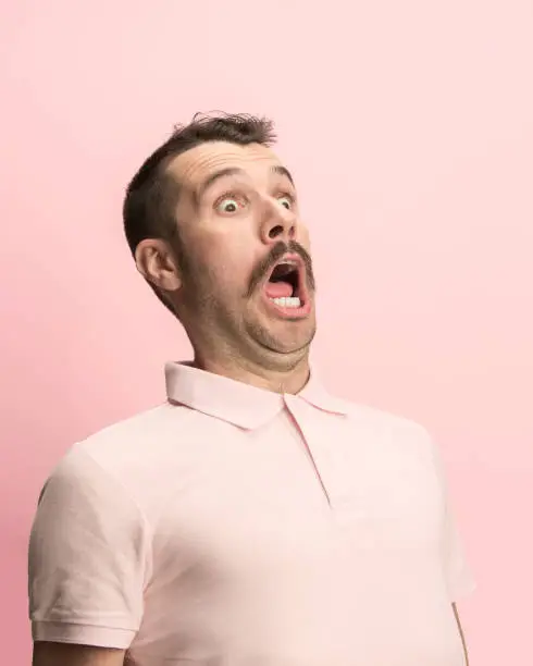 Photo of The man screaming with open mouth isolated on pink background, concept face emotion