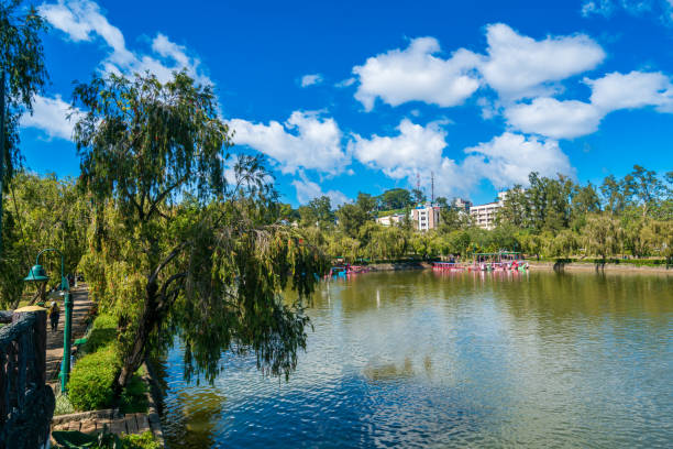 Baguio, Philippines - December 1, 2016: view showing tourist attraction in Baguio, Burnham Park, bridge, people riding boats in the river, trees, buildings and houses can be seen on the background