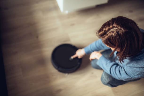 istock Girl turning on robot vacuum cleaner 1072540580