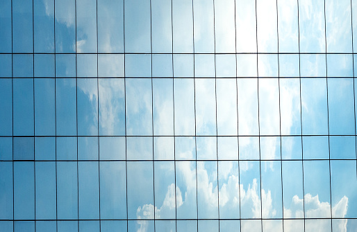 Reflection of blue sky and cloud on glass building. Bright light on glass building.