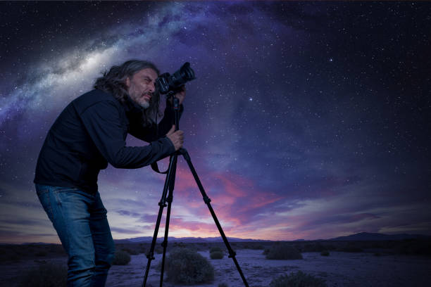 photographer taking photo of night sky man standing at camera on tripod under a starry sky astrophotography stock pictures, royalty-free photos & images