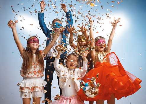 Adorable kids have fun together throw colourful confetti at birthday party. They playing together in different games, spending time in decorated studio. Children and events concept