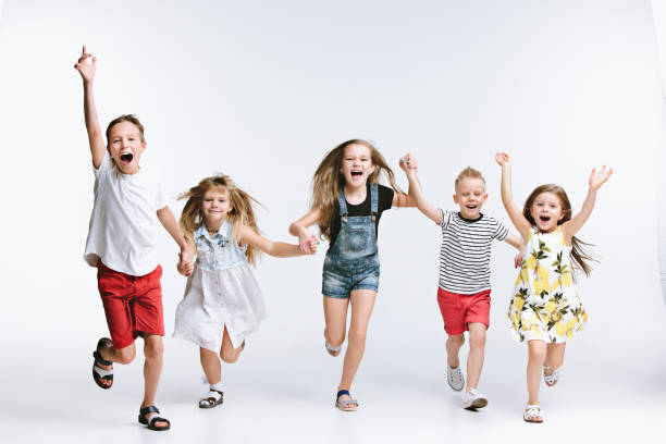 Group fashion cute preschooler kids friends posing together and looking at camera white background Group of fashion cute preschooler kids friends running together and looking at camera on a white studio background. The friendship, fashion, summer concept. Space for text. boy and girl looking at camera stock pictures, royalty-free photos & images