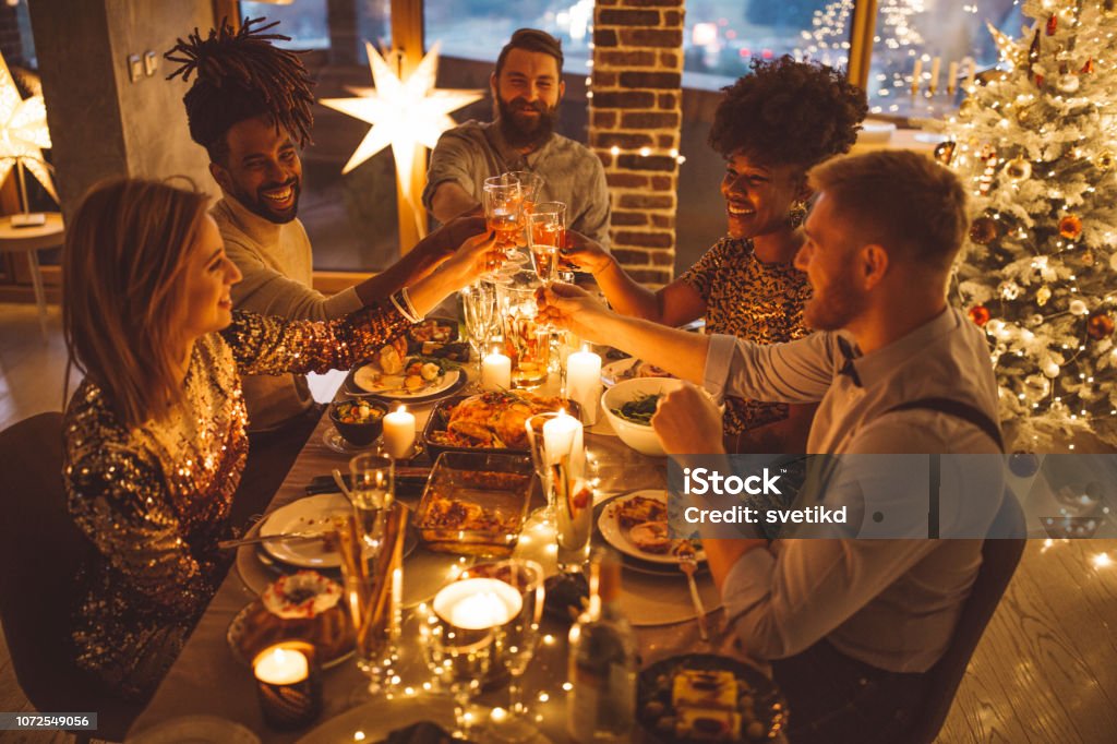 Friends on new year dinner party Multi ethnic group of friends having new year dinner party, everyone enjoying in food and drink Christmas Stock Photo