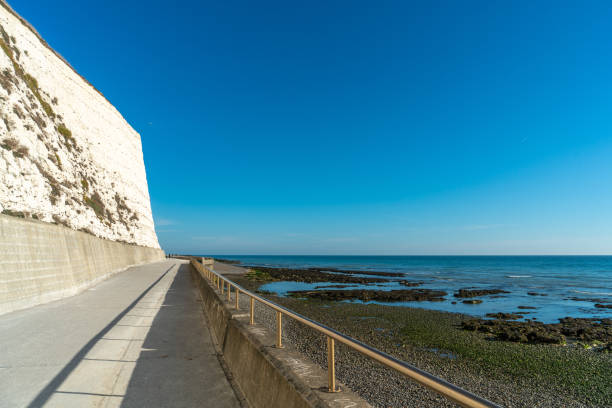 istock Saltdean beach seafront and white sandstone chalk cliffs with two local people walking for exercise. 1072550942
