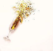 Champagne glass with golden glitter on pink background. Flatlay. Copy space. New Year concept