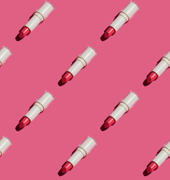 seamless mönster av röda tonade läppbalsam läppstift platt låg på rosa papper. - lipstick bildbanksfoton och bilder