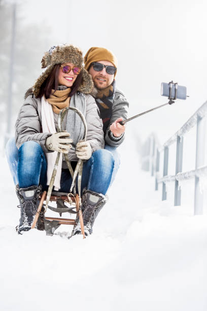 istock Young couple taking selfies on sledge in snow 1072561486
