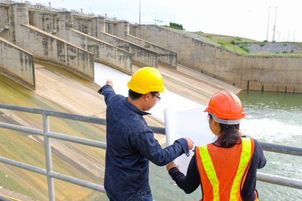 Men and woman meeting with Engineers and supervisors are standing reading the blueprints at the construction site stock photo