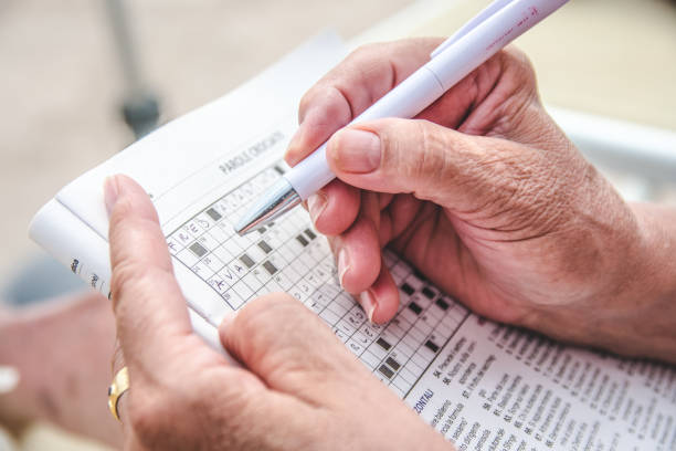 Elder person completing a crosswords View of an old person completing a crossword puzzle. crossword stock pictures, royalty-free photos & images