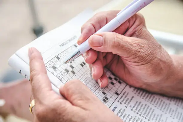 View of an old person completing a crossword puzzle.