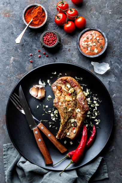 istock fried pork steak with garlic and thyme in dark plate on dark background 1072580546