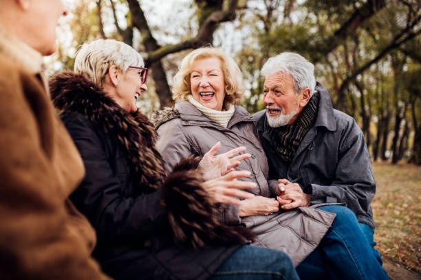 istock Two happy senior couples sitting in the park laughing 1072580624