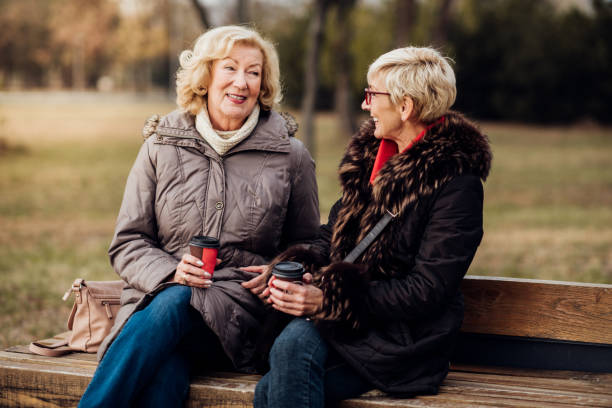 istock Senior women sitting in a park drinking coffee 1072585006