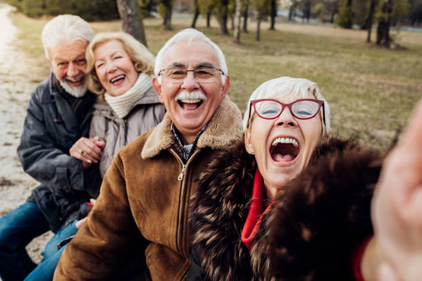 istock Two happy senior couples laughing on a bench in a park 1072586830