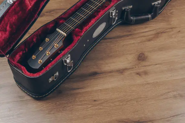 Photo of an acoustic guitar in the brown leather guitar hard case