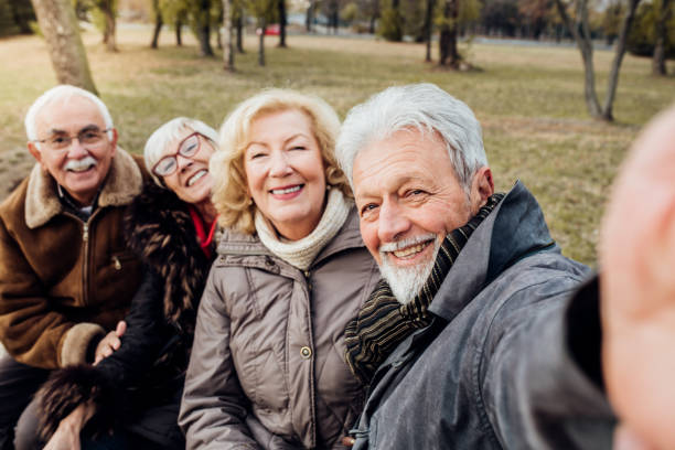 istock Two smiling senior couples on a bench in a park 1072586952