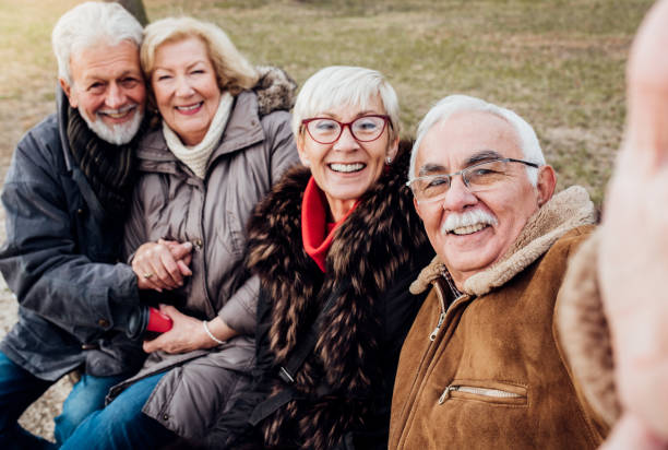 istock Two happy senior couples on a bench in a park 1072586958