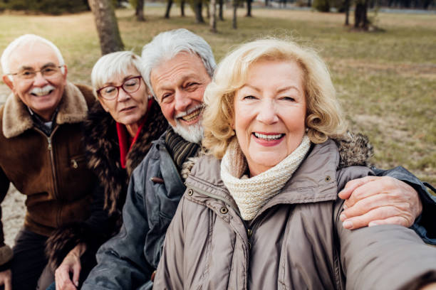 istock Two cheerful senior couples on a bench in a park 1072587000
