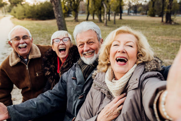 ältere ehepaare lachen auf einer bank in einem park - senior adult retirement mature adult couple stock-fotos und bilder