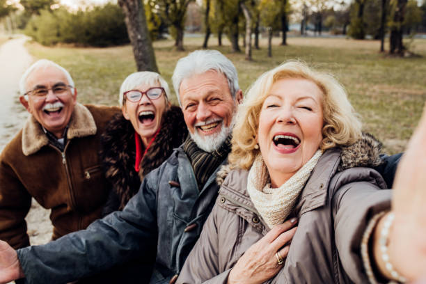 parejas seniors riendo en un banco de un parque - mature adult couple caucasian outdoors fotografías e imágenes de stock