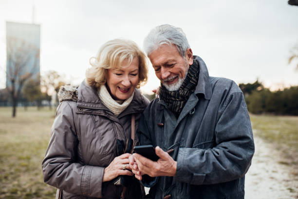 istock Senior couple standing in a park looking at a cell phone 1072597270