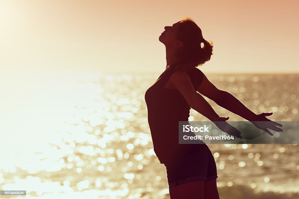 Woman relaxing in summer sunset sky at the beach Woman relaxing in summer sunset sky at the beach, with open hands Recovery Stock Photo