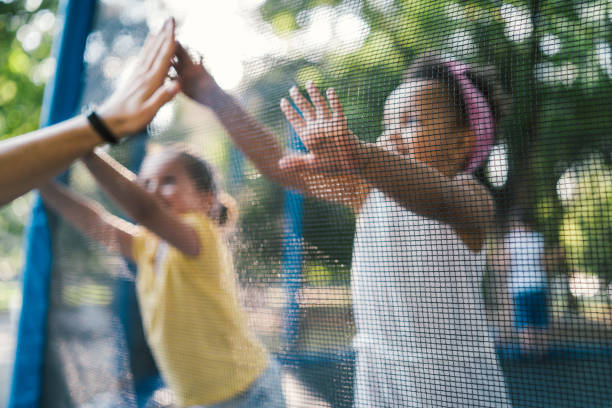 Sister time! Two girl playing at trampoline safety net stock pictures, royalty-free photos & images