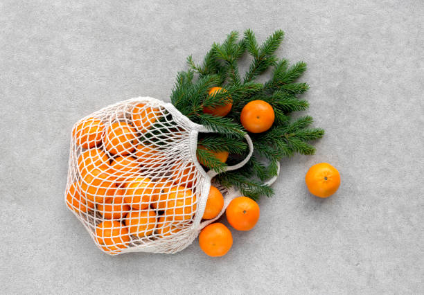 Mesh shopping bag with clementines and fir branches. stock photo
