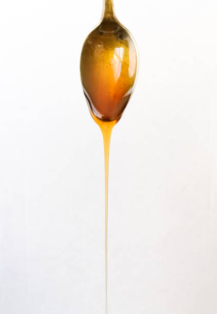 istock close-up silvery and vintage spoon with honey falling, on white background 1072625120