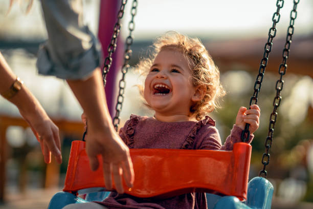 adorable niña divirtiéndose en un columpio - parque infantil fotografías e imágenes de stock