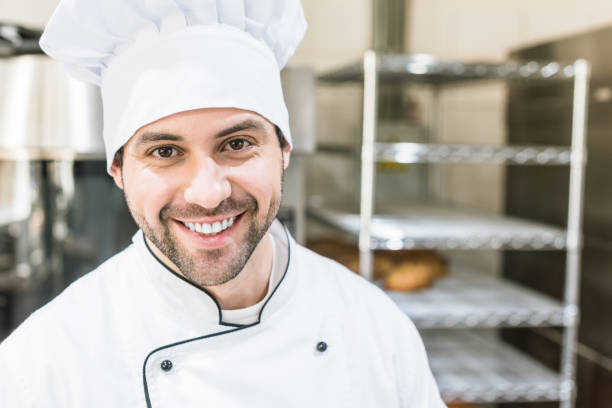 istock Handsome cook in chefs uniform smiling in bakehouse 1072630544
