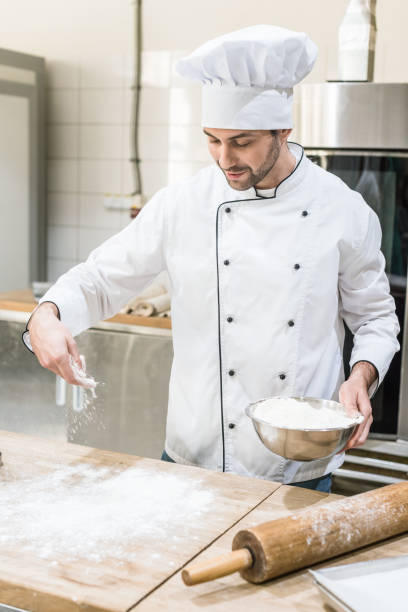 istock Baker in white chefs uniform cooking dough on wooden table 1072630562