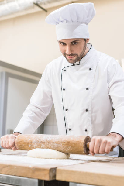 istock Chef rolling out dough with rolling pin on wooden table 1072630584