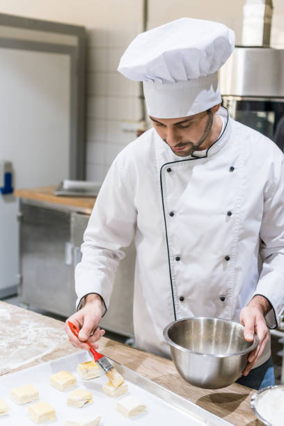istock male baker oiling dough pieces with basting brush at kitchen 1072630644