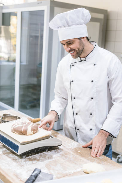 istock Smiling baker weighing uncooked dough on kitchen scales 1072630658