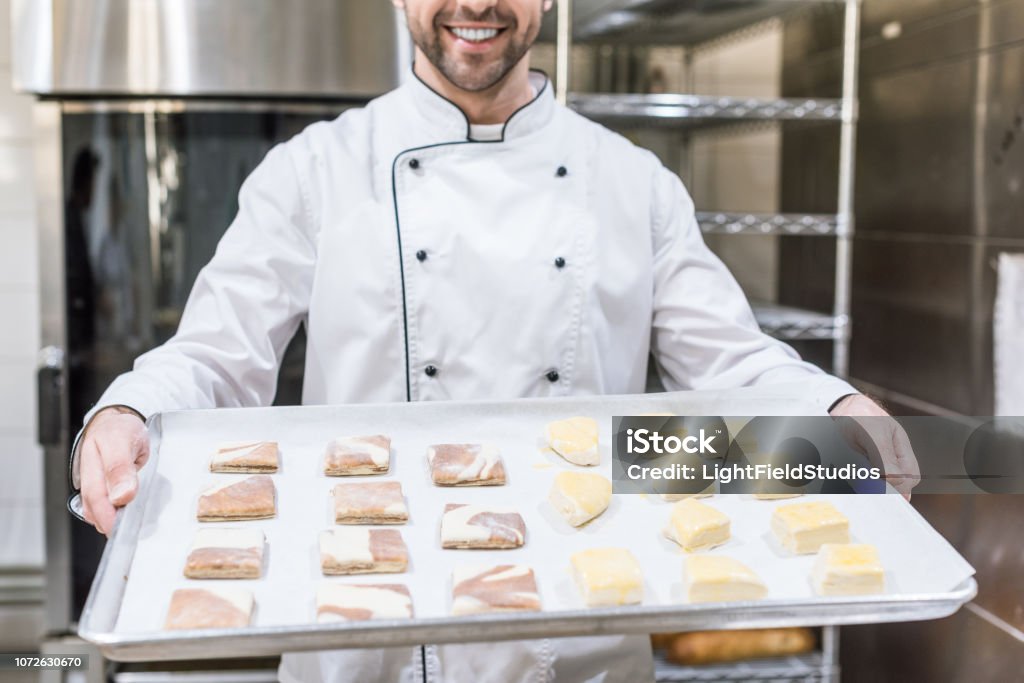 Ansicht von lächelnden Cook holding Backblech mit Rohteig beschnitten - Lizenzfrei Backblech Stock-Foto