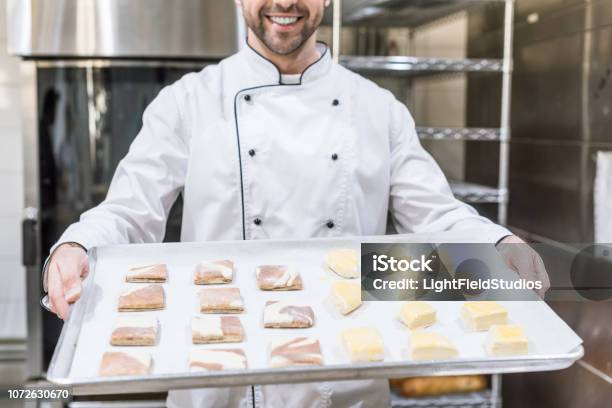 Ansicht Von Lächelnden Cook Holding Backblech Mit Rohteig Beschnitten Stockfoto und mehr Bilder von Backblech