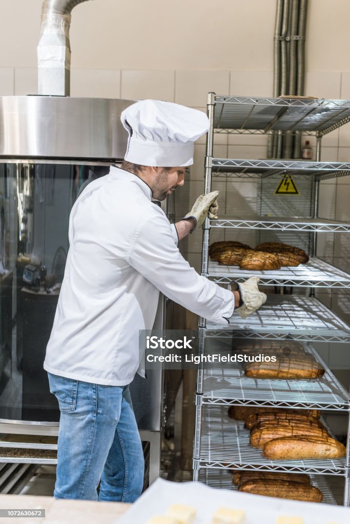 Seitenansicht des männlichen Chef hält Rack mit Brot - Lizenzfrei Arbeiten Stock-Foto