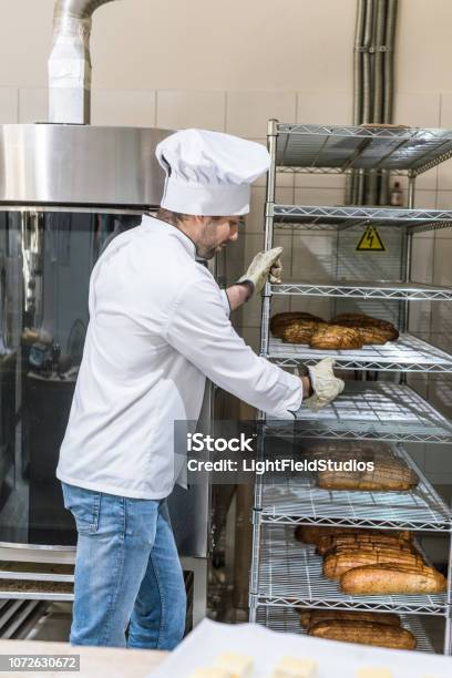 Seitenansicht Des Männlichen Chef Hält Rack Mit Brot Stockfoto und mehr Bilder von Arbeiten