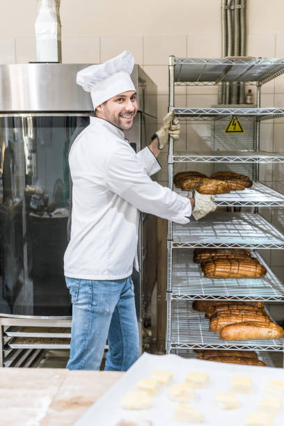 istock Side view of smiling chef taking out rack with bread 1072630692