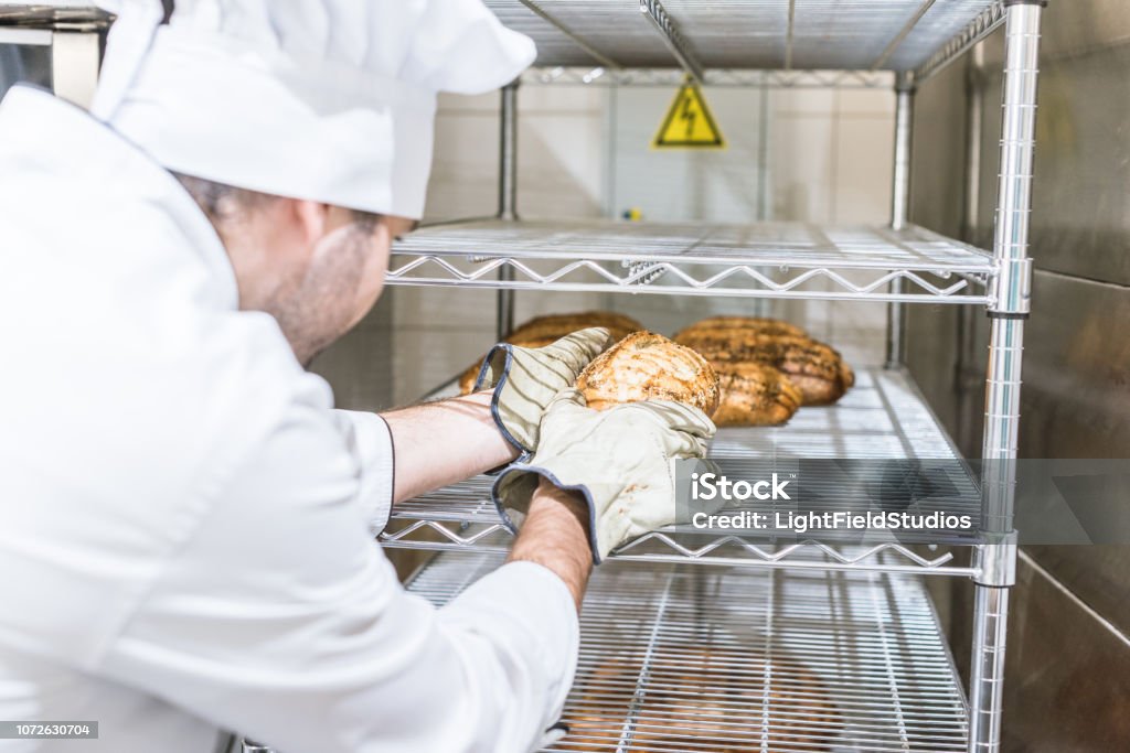 männliche Bäcker in weißen Köche Uniform, frisches warmes Brot in rack - Lizenzfrei Backen Stock-Foto