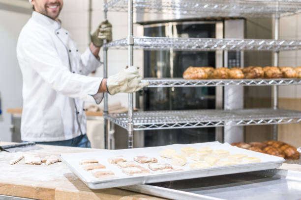 istock smiling male baker in white chefs uniform working at kitchen 1072635500