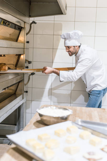 istock concentrated baker taking out hot bread from oven at kitchen 1072635504