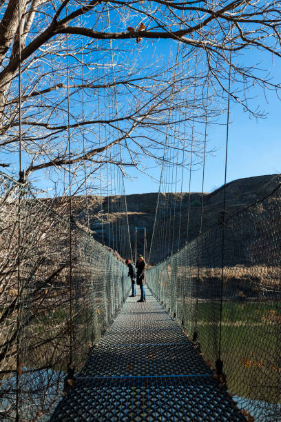 Star Mine Suspension Bridge in Drumheller Valley of the Canadian Badlands, Alberta, Canada People walking across the Star Mine Suspension Bridge in Drumheller Valley of the Canadian Badlands in Alberta, Canada. Multiple files stitched. drumheller stock pictures, royalty-free photos & images